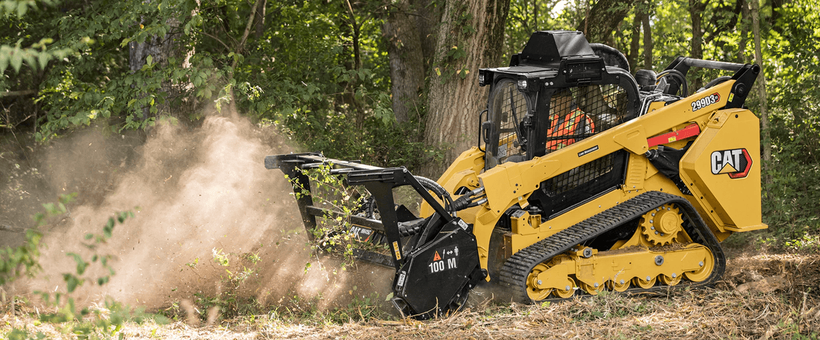 Heavy-duty skid steer with forestry mulcher attachment clearing dense forest land